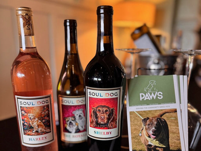 Two guests raising glasses of red wine at a Soul Dog Wines event.